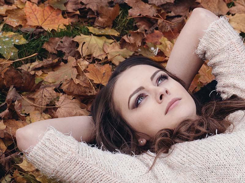 Kvinde ligger på jorden og kigger op i himlen en dejlig efterårs dag